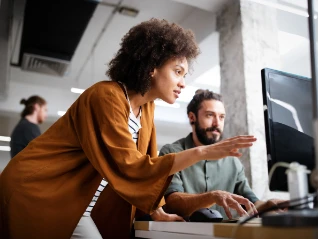 Two employees having a discussion at a desk